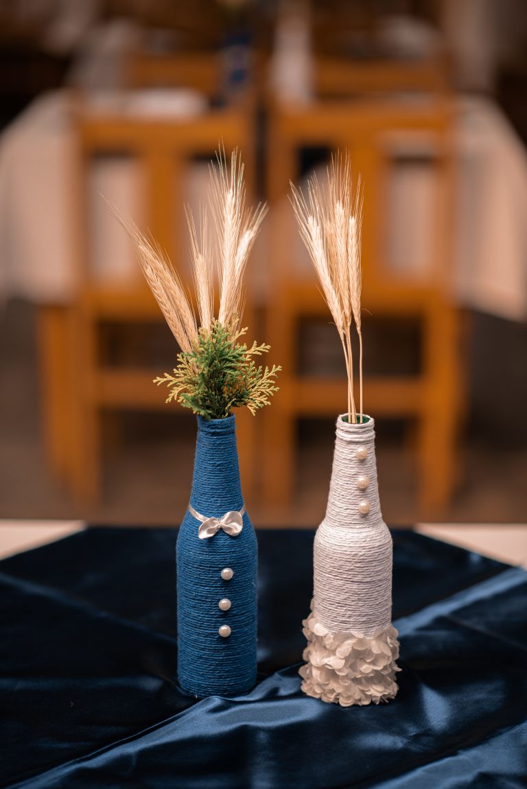 Stylish decorative bottles with dried grass arrangement on a table. Des bouteilles décoratives élégantes avec un arrangement d'herbe séchée sur une table.