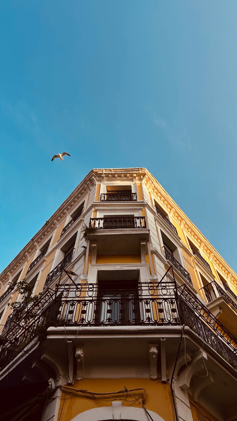 Low angle view of a traditional building with balconies against a clear blue sky. Vue en contre-plongée d'un bâtiment traditionnel avec balcons contre un ciel bleu dégagé.