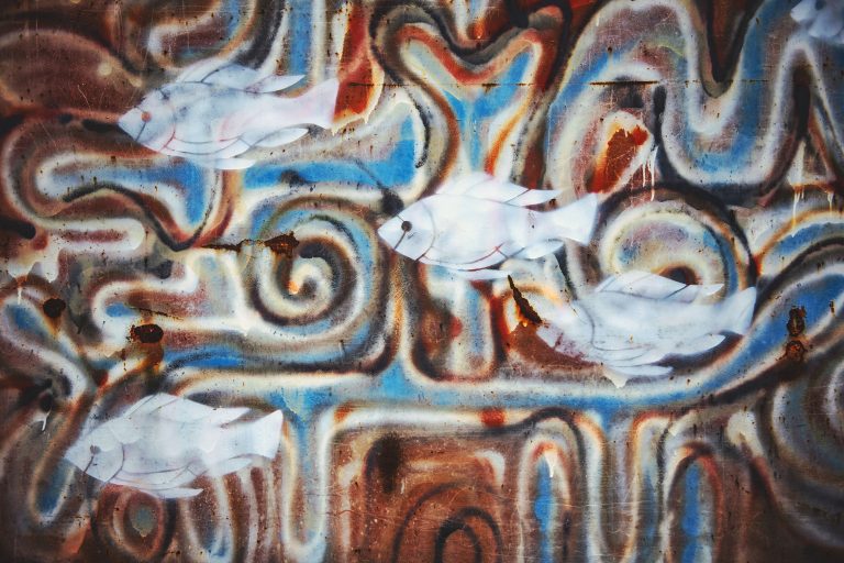 Fresque murale de street art colorée représentant un poisson abstrait sur un mur texturé, mettant en avant une créativité vibrante.