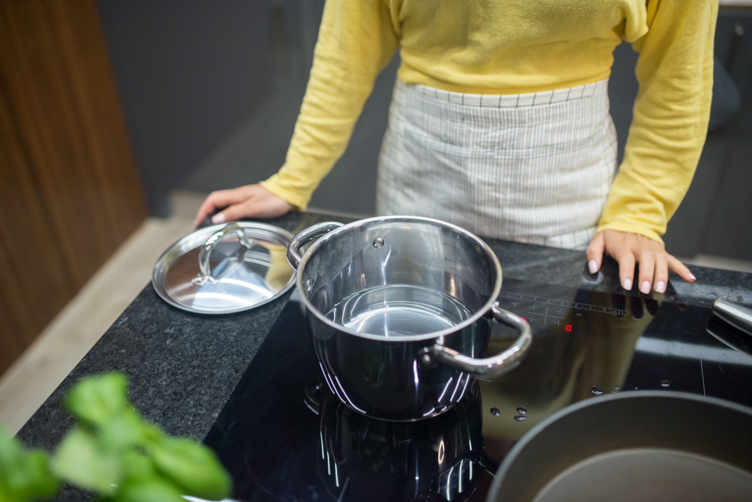Femme cuisinant avec pot inox plaque induction