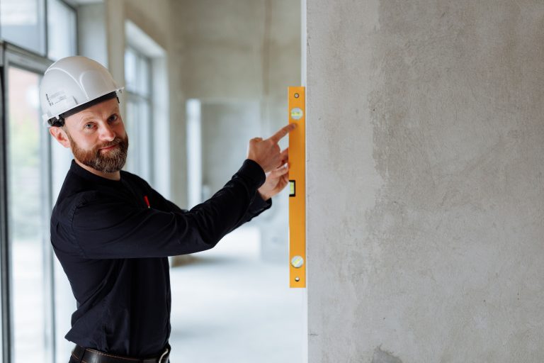 Ingénieur avec casque vérifiant un mur de chantier