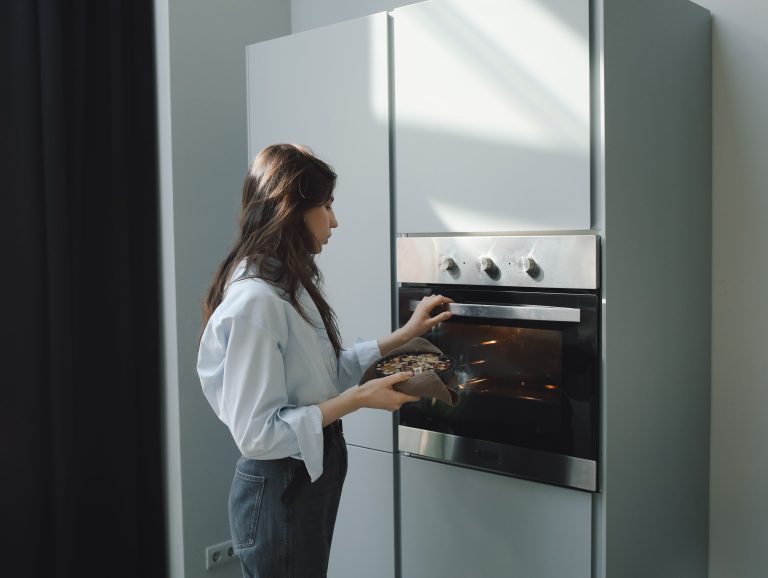Jeune femme enfournant un plat dans son four