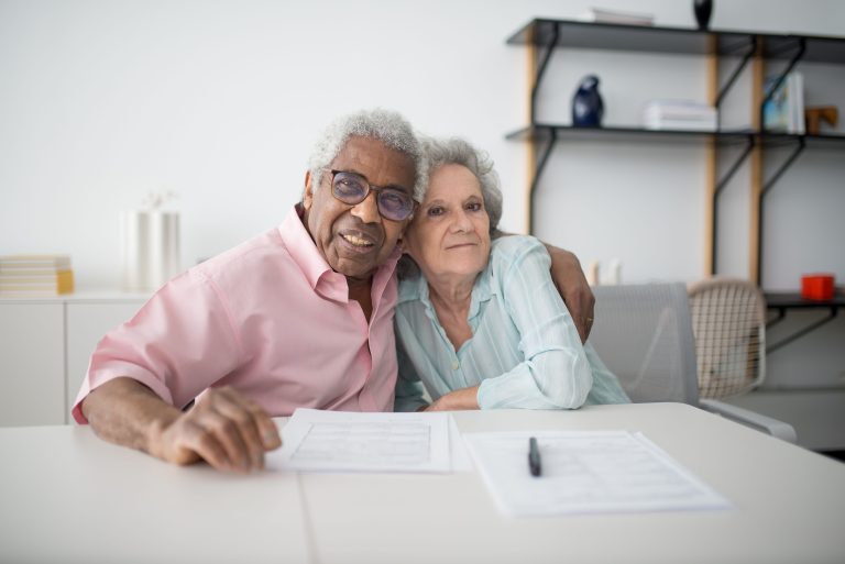 Couple de seniors souriants consultant documents financiers