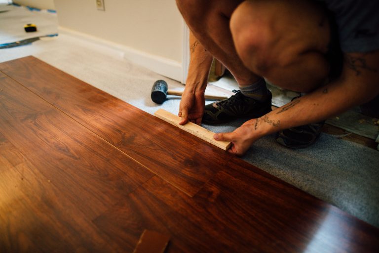 Artisan posant du parquet flottant avec maillet
