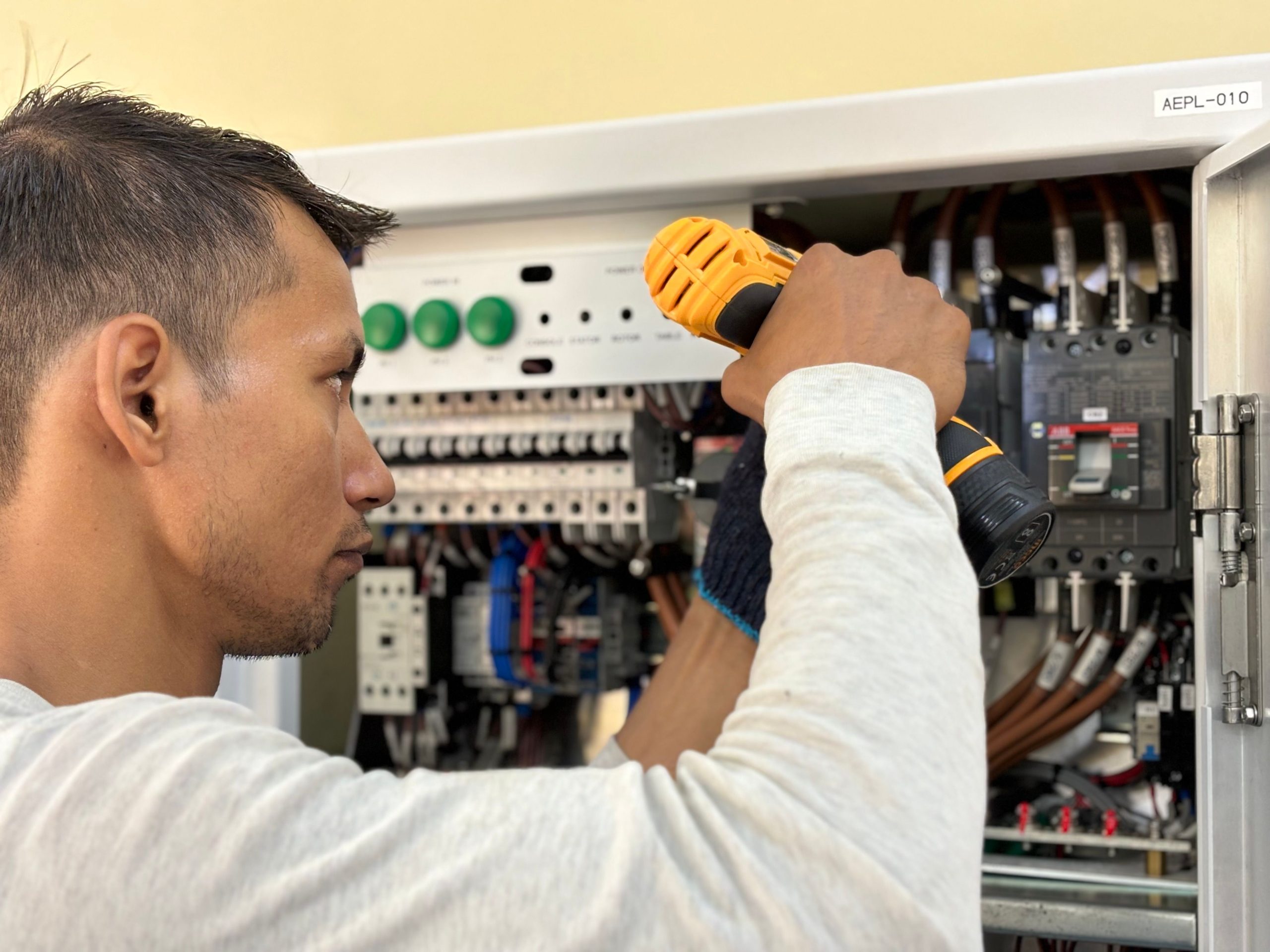 Électricien perçant un tableau de disjoncteurs